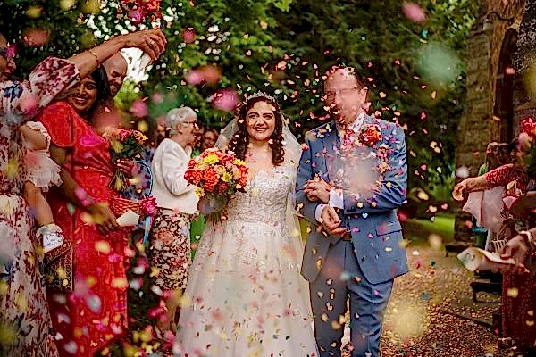Dodford Manor Wedding Photographer captures a bride and groom surrounded by confetti at their wedding.
