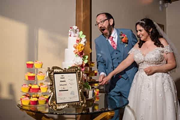 A bride and groom cutting their wedding cake at Dodford Manor captured by a professional Wedding Photographer.