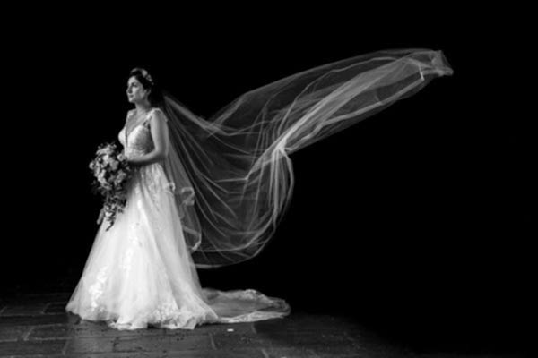 A Dodford Manor Wedding Photographer captured a mesmerizing black and white photo of a bride with her veil blowing in the wind.