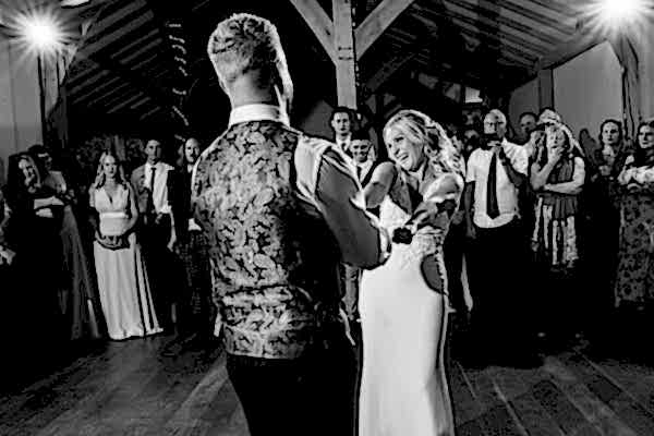 A bride and groom sharing their first dance in a barn captured by Dodford Manor Wedding Photographer.