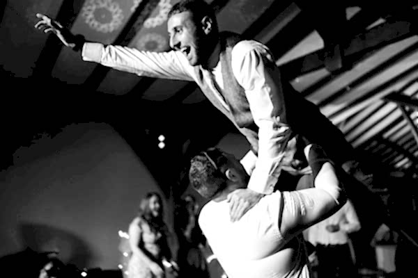 A man is being carried by another man on the dance floor at Dodford Manor Wedding.