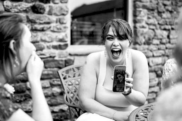 A Dodford Manor Wedding Photographer captures a woman taking a selfie with a cell phone.