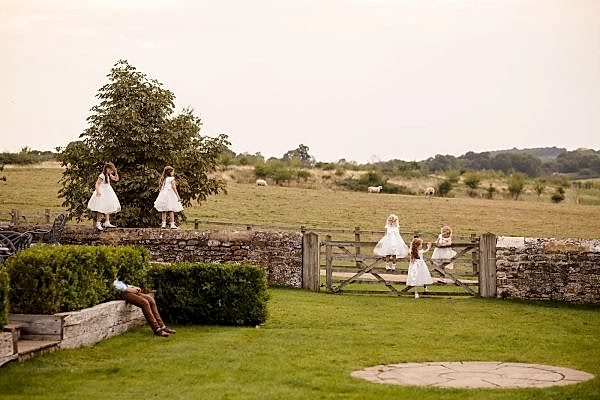 A group of bridesmaids in white dresses standing in a field at Dodford Manor.