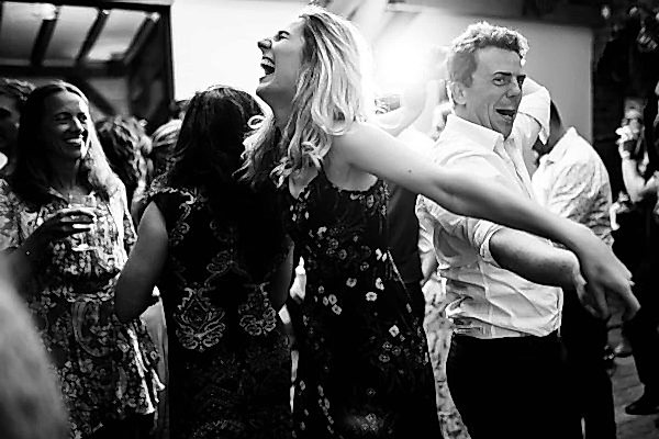 A black and white photo capturing the joyous celebration of people dancing at a Dodford Manor wedding.