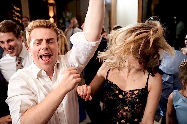 A lively group of people dancing at a Dodford Manor wedding reception.