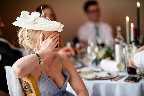 A woman wearing a hat at a wedding.