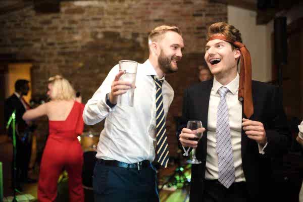 Dodford Manor Wedding Photographer capturing two men laughing at a wedding reception.