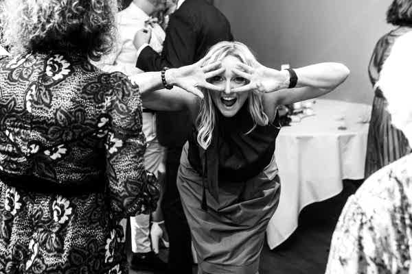 Dodford Manor wedding photographer captures a black and white photo of a woman making faces at a party.