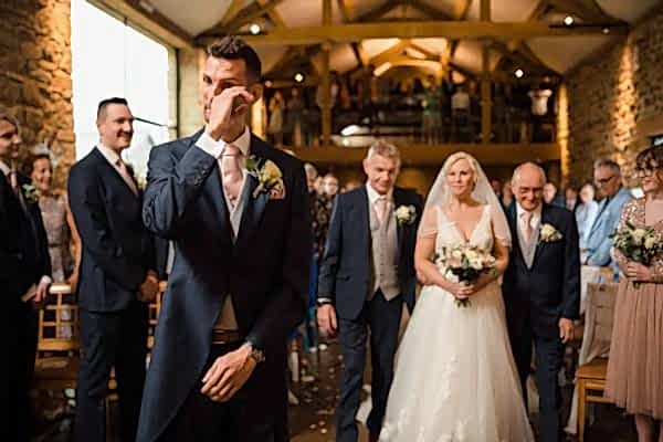 A bride and groom, captured by a Dodford Manor Wedding Photographer, joyfully walking down the aisle at their wedding.