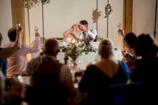 A bride and groom celebrating their marriage with a joyful toast during their Dodford Manor wedding reception, captured by a talented wedding photographer.