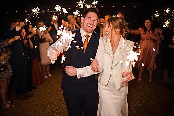 A bride and groom captivated by the mesmerizing sparklers at their Dodford Manor wedding reception.