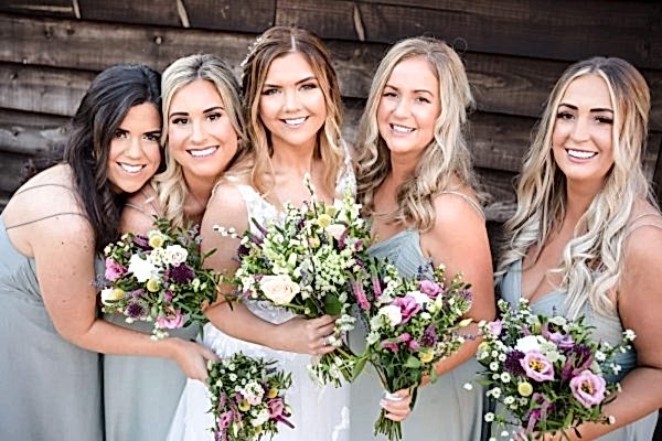 Dodford Manor Wedding Photographer capturing bridesmaids holding bouquets in front of a wooden wall.