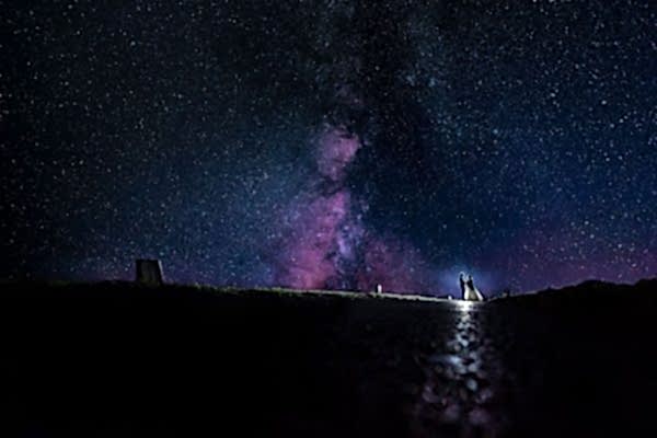 Dodford Manor Wedding Photographer captures a couple standing under a mesmerizing starry sky with the milky in the background.