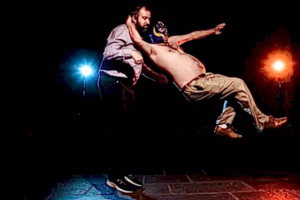 Two men, captured beautifully by a Dodford Manor wedding photographer, showcasing their incredible acrobatics in a dark room.