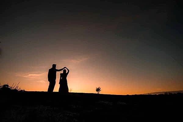 A stunning silhouette of a bride and groom at sunset, captured by a talented Dodford Manor wedding photographer.