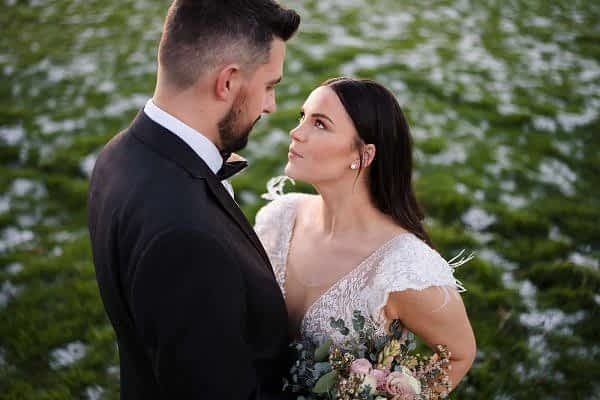 Dodford Manor Wedding Photographer captures a beautiful bride and groom standing in a field of flowers.
