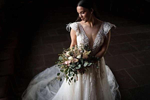 A bride holding a bouquet in a dark room captured by the Dodford Manor Wedding Photographer.