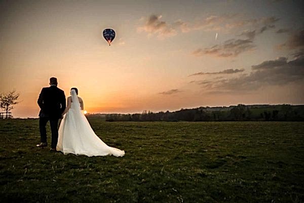Wedding couple watching sunset and hot air balloon.