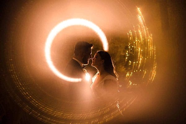 A bride and groom captured in a circle of light by Dodford Manor Wedding Photographer.