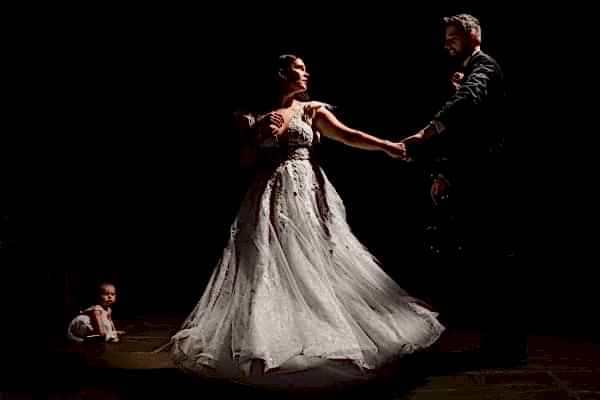 A bride and groom gracefully dancing in a dimly lit room captured by the talented Dodford Manor Wedding Photographer.