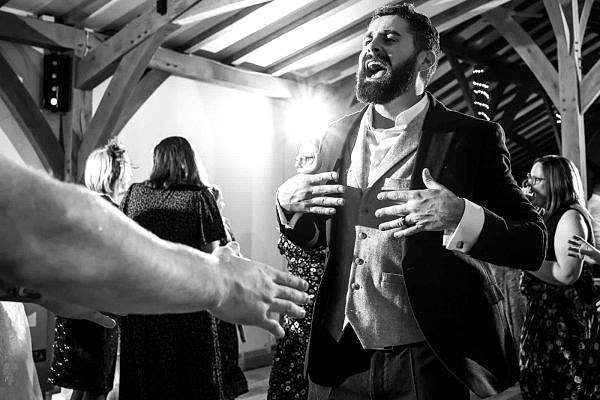 Dodford Manor Wedding Photographer captures a black and white photo of a man dancing at the wedding.