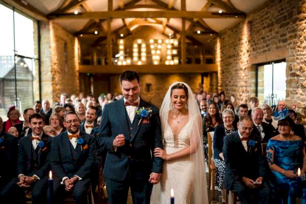 Dodford Manor Wedding Photographer capturing a beautiful bride and groom walking down the aisle at their wedding.