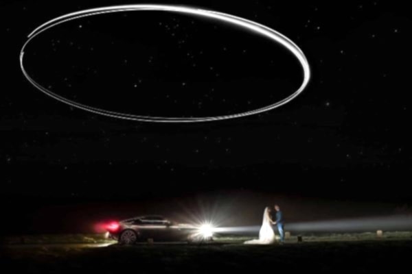 A bride and groom standing in front of a car under a starry sky captured by a Dodford Manor Wedding Photographer.