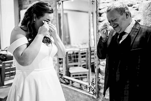 A tearful bride gazes at her reflection in front of a mirror on her wedding day.