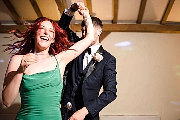 A Dodford Manor wedding photographer captures the magical moments of a man and woman dancing at a wedding reception.