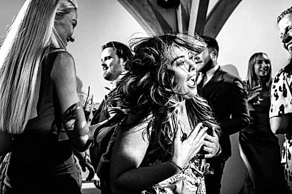 Dodford Manor Wedding Photographer captures a mesmerizing black and white photo of a group of people joyously dancing at a wedding.