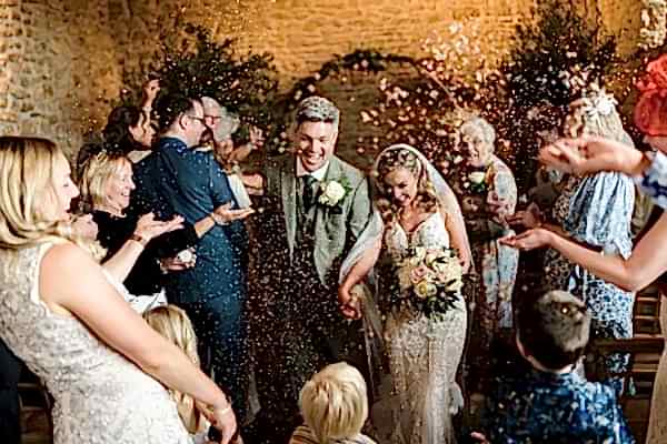A Dodford Manor Wedding Photographer captures the magical moment of a wedding ceremony as confetti is joyfully thrown at the bride and groom.