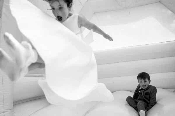 A boy and girl enjoying a white bouncy castle at Dodford Manor Wedding.