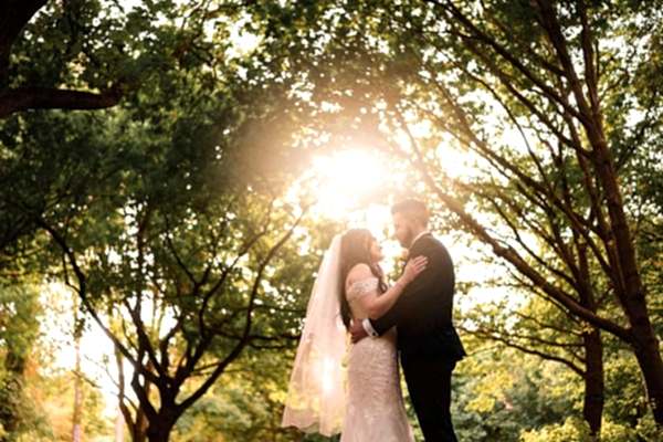 Dodford Manor Wedding Photographer captures the magical embrace of a bride and groom amidst the enchanting trees at sunset.