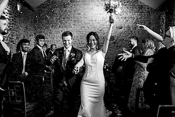 Dodford Manor Wedding Photographer: Capture the magical moment of a bride and groom walking down the aisle, surrounded by joyful confetti.