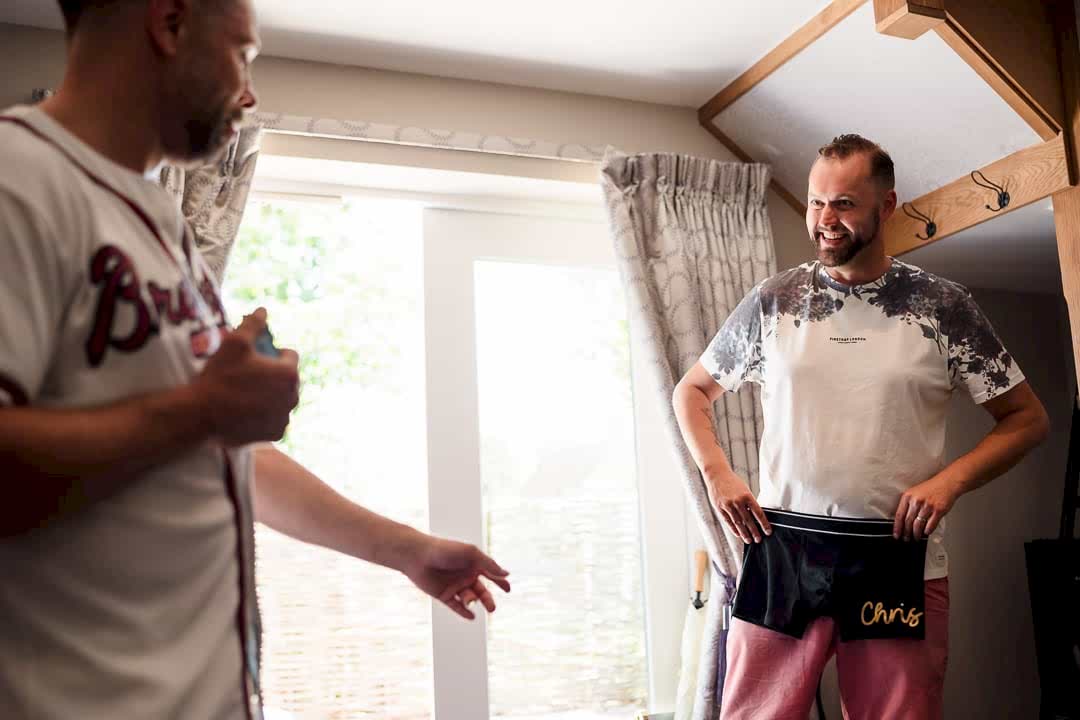 Men laughing indoors, holding personalised shorts.